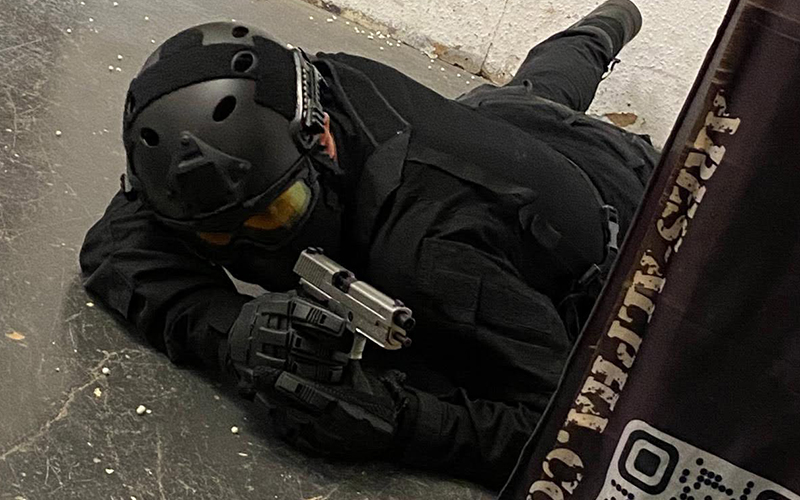 An Airsofter laying on the ground with a GBB pistol