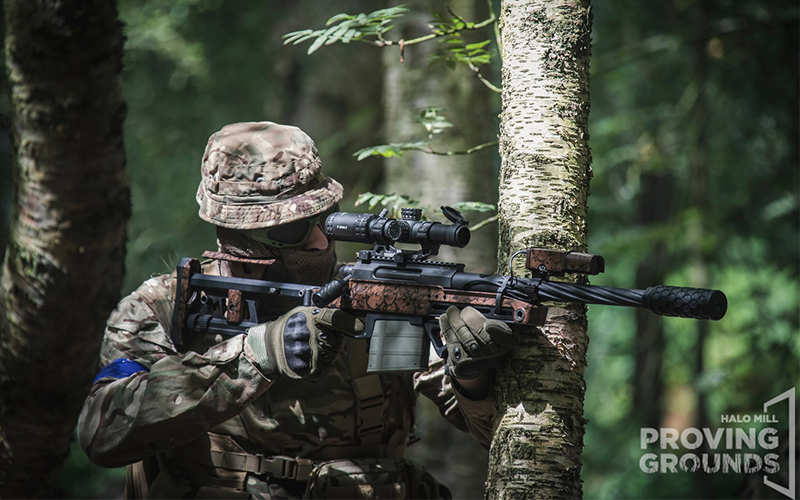 An Airsofter dressed in camouflage looking down his scope