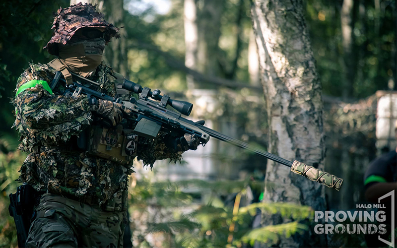An Airsofter in a ghille suit holding a sniper rifle